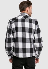Zwart-wit geruit flanel shirt met lange mouwen, knoopmanchetten en een afgeronde zoom. Zachte textuur en klassiek ruitpatroon.