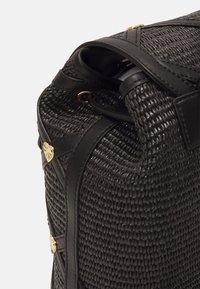 Czarna pleciona torebka z teksturowego materiału, ze skórzanymi akcentami i złotymi detalami. Zaokrąglony kształt o sztywnej konstrukcji.