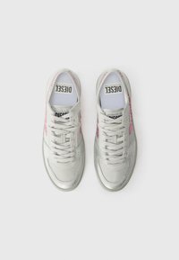 Des baskets grises avec des accents argentés métalliques et des détails en paillettes roses. Elles présentent des lacets plats et un logo sur la languette. Texture lisse.