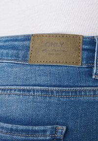 Ljusblå denimjeans med en blekt textur. Har en sydd brun läderetikett med "ONLY" och en bakficka.