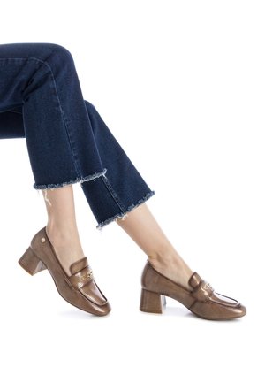 Mocasines de cuero marrón con tacón bloque y acabado brillante, que presentan un acento decorativo dorado en la parte delantera y un diseño de punta redonda.