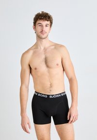 Black boxer shorts with a white "BJÖRN BORG" logo waistband, made from a soft material, featuring a fitted design and short leg length.