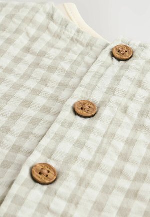 Helles grau und weiß kariertes Stoffkleidungsstück mit Holzknöpfen mit graviertem Design. Weiche Textur, runder Ausschnitt und genähte Kanten.