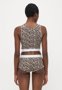 Krajkový crop top s leopardím vzorom a zodpovedajúcimi vysokými nohavičkami. Vyrobené z hladkého materiálu s bielym elastickým pásom s logom.