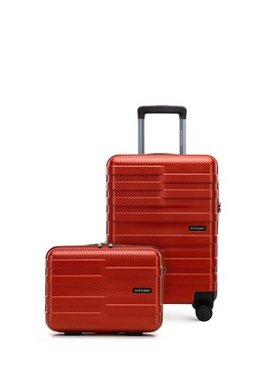 Dva červené pevné kufry s texturovanými horizontálními liniemi, jeden s teleskopickou rukojetí a kolečky, oba značky "Wittchen".