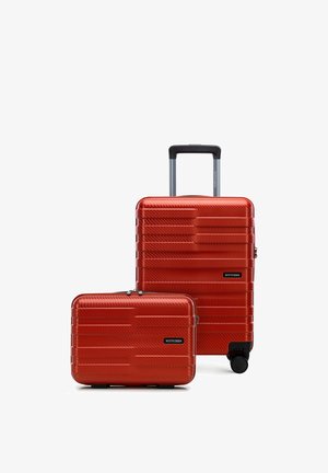 Dva červené pevné kufry s texturovanými horizontálními liniemi, jeden s teleskopickou rukojetí a kolečky, oba značky "Wittchen".