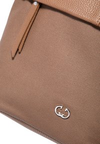 Brun texturerad läderväska med en slät överdel, silverlogotyp och två läderdetaljer. Kompakt design med en minimalistisk estetik.