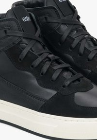 Czarne skórzane sneakersy za kostkę z teksturowanymi akcentami, czarnymi sznurówkami i kontrastującą białą gumową podeszwą. Wyróżnia się logo na języku.