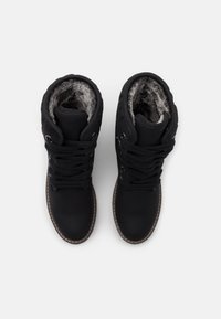 Bottines noires avec un extérieur en simili cuir texturé, un intérieur doublé de fourrure, un bout rond et des lacets circulaires avec des œillets en métal.