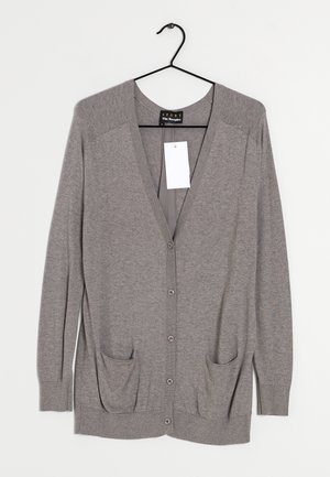 Harmaa neuletakki v-pääntällä, pitkillä hihoilla ja napp closurella. Sisältää kaksi etutaskua ja ripustettavan lipukkeen.