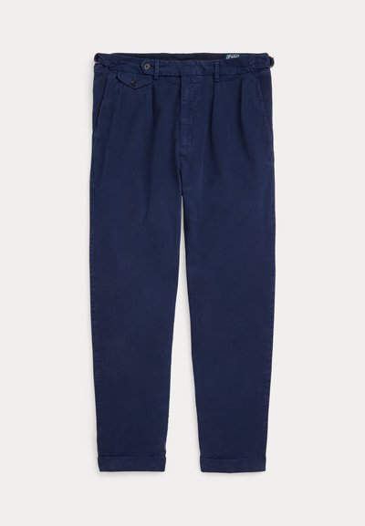 Marineblaue, taillierte Hose mit Gürtelschlaufen, seitlichen Verstelllaschen, Vordertaschen und einer mit Knopf versehenen Klappentasche an der rechten Hüfte.