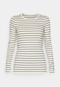 Långärmad topp i krämfärgad med svarta horisontella ränder. Har en rund halsringning och en åtsittande design, tillverkad av ett mjukt, elastiskt tyg.