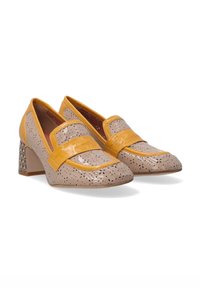 Beige lakeret sko med perforeret design og gule accenter. Høj blokhæl med et geometrisk mønster. Slip-on stil med bred rem.