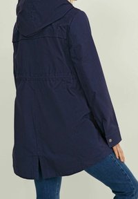 Námořnická kapucí bunda s volnějším střihem, s knoflíkovým manžetem, zadním rozparkem a texturovaným matným povrchem.