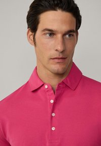Pánská polokošile v jasně růžové barvě, s límečkem, zapínáním na pět knoflíků a hladkým, texturovaným materiálem.