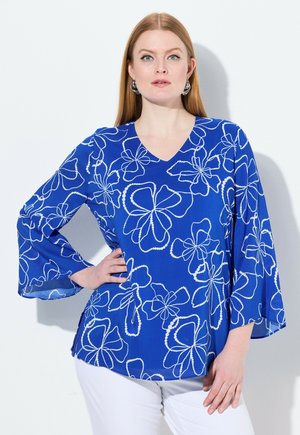 Blusa floreale blu con scollatura a V e maniche a campana, caratterizzata da motivi floreali contornati di bianco e spacchi laterali all'orlo.