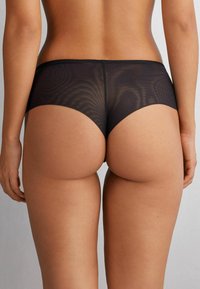 Black mesh hipster underwear with smooth edges and a low-rise design, featuring a semi-transparent fabric and no visible hardware.