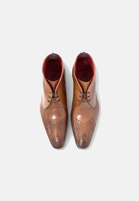 Zapatos de vestir de cuero en marrón, con un diseño elegante, detalles de brogue y un forro interior rojo. Cierre con cordones.