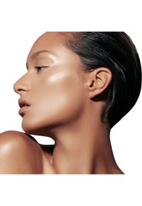 Vista de perfil de un rostro con piel suave y radiante, pómulos definidos y cabello corto y oscuro, sobre un fondo blanco.