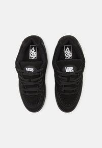 Crni nubuk tenisice s niskim dizajnom, koje imaju okrugli vrh, ravne vezice i Vans logo na jeziku i bočnoj strani.