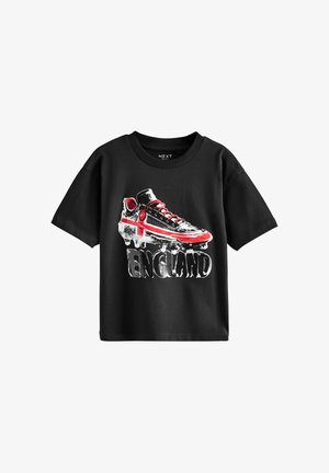 Fekete, rövid ujjú póló, amelyen egy piros kereszttel díszített focicipő grafika látható, alatta az "ENGLAND" felirattal.