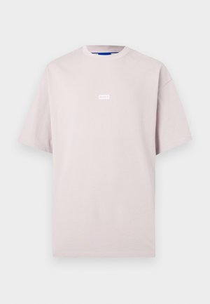 Helebeežikas üle suuruses T-särk lühikeste varrukatega ning väikese keskse "HUGO" logoga rinnal, tasase taustaga.