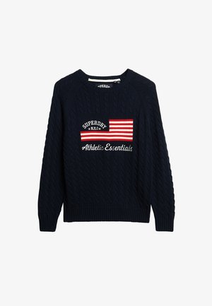 Suéter de punto azul marino con patrón de trenzas, que cuenta con un parche de logo frontal con rayas rojas y blancas y el texto "SUPERDRY N.Y.C." y "Athletic Essentials."