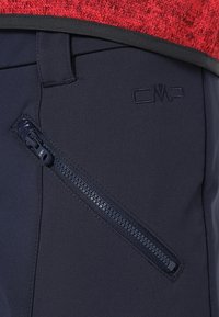 Granatowe spodnie softshell z boczną kieszenią na zamek, teksturowanym materiałem oraz subtelnym logo CMP na pasku. Nowoczesny design z funkcjonalnymi akcentami.