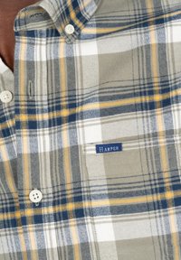 Camisa de cuadros con una mezcla de colores gris, blanco, azul y amarillo. Fabricada con tela tejida, cuenta con cierres de botón y una etiqueta que dice "Harper."