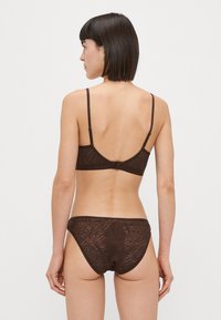 Rjav niz spodnjega perila z v textured vzorcem, tankimi nastavljivimi naramnicami in nizkim pasom, izdelan iz mehke, raztegljive tkanine.