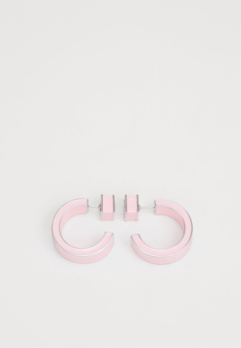 Paire de boucles d’oreilles créoles de taille moyenne en rose pastel avec bords argentés sur fond blanc uni.