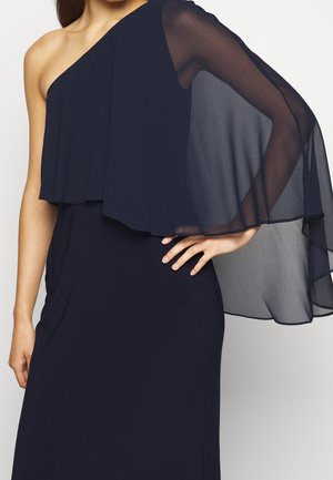 Robe bleu marine à une épaule avec un voile fluide transparent au niveau du décolleté ; texture lisse, silhouette ajustée et détail de pli subtil.