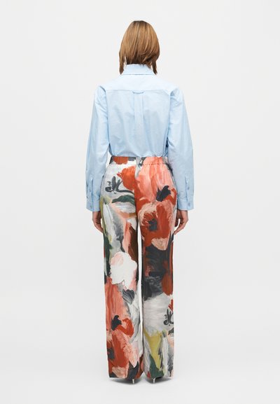 Ανοιχτό μπλε πουκάμισο με κουμπιά συνδυασμένο με φαρδιά παντελόνα με λουλουδάτο μοτίβο σε αποχρώσεις κόκκινου, λευκού και πράσινου, με ελαστική μέση.