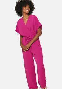 Fuchsia wrap jumpsuit with short sleeves, tie waist, and wide legs. Soft texture, smooth fabric, and a relaxed fit throughout.