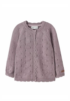 Liliowy sweter kardigan z dzianiny z karbowanym dołem, zapinany na guziki z przodu, z dekoracyjnymi dziurkami na całej powierzchni. Posiada długie rękawy oraz metkę na rękawie.