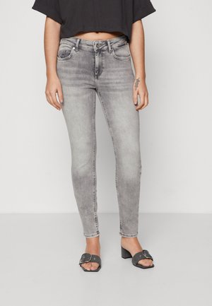 Grå skinny jeans med falmet finish, klassisk fem-lommers design og lynlås. Brukt med svarte hælhæler.