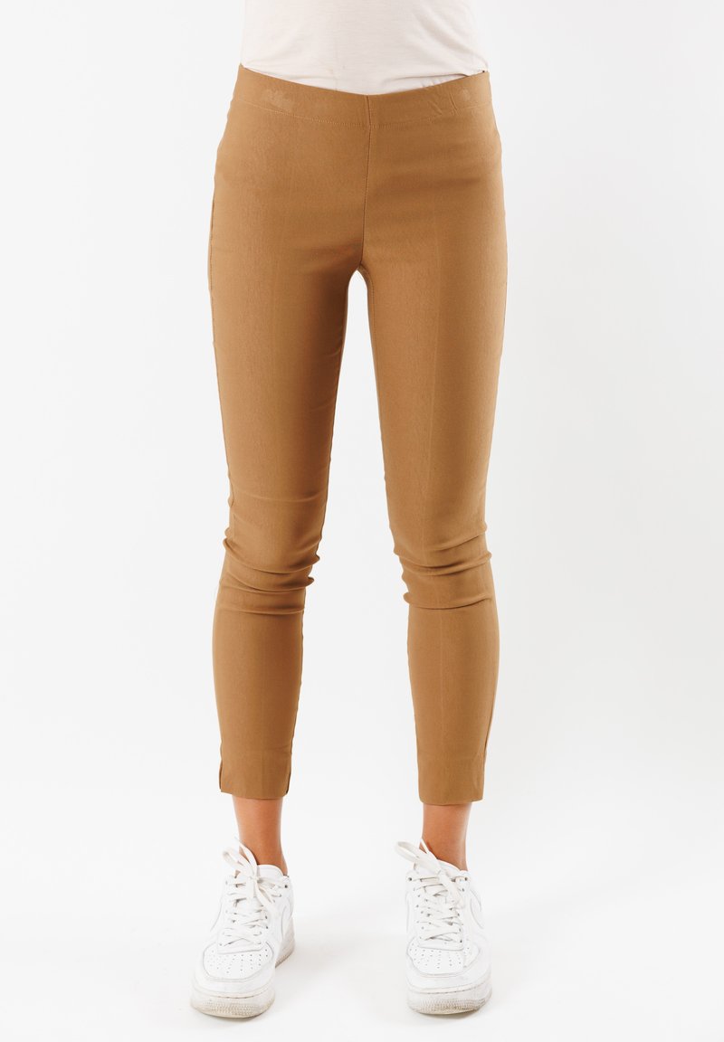 Leggings attillati color sabbia con una texture liscia e orlo accorciato. Abbinati a sneakers bianche, per un look pulito e casual.