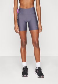 Grå idrettsshorts med høy livlinje, glatt materiale, kontrasterende rosa lomme-detalj, og en hvit logo foran.