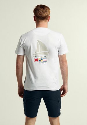 Camiseta blanca de algodón con un gráfico de velero en la parte posterior, junto con letras en rojo, azul y amarillo que dicen "VLC Sailing".