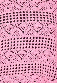 Rosa gestrickter Stoff mit einem komplizierten Spitzenmuster, das Diamant- und Gittermotive aufweist und eine weiche, strukturierte Oberfläche zeigt.