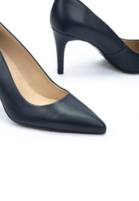 Tacones altos de cuero azul marino con punta afilada y un tacón de aguja delgada. Textura suave y un diseño clásico y minimalista.