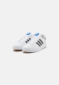Hvite sneakers med svarte og grå striper, teksturert skinnoverdel, gummisåle og blå logoakenter på tungen.