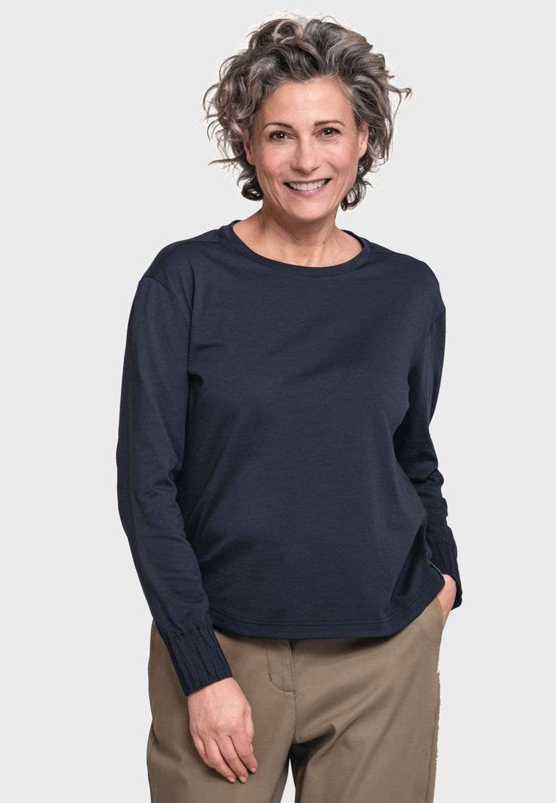 Marineblaues Langarmoberteil aus Baumwolle, mit runder Ausschnitt und gerafften Manschetten. Getragen mit beigen Hosen.