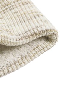 Hellfarbiger Strickstoff mit strukturiertem Muster und kontrastierendem geripptem Rand, ausgestattet mit weichen Fasern und einem gemütlichen Erscheinungsbild.