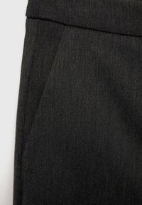 Pantalons gris foncé en tissu texturé, dotés d'une taille lisse et d'une poche avant en angle. Design simple et minimal.