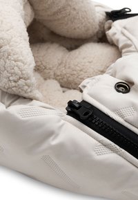 Witte gewatteerde jas met een fluffy crème fleece voering, zwarte rits en zilveren hardware accenten. Bevat een textiel buitenstof met patronen.