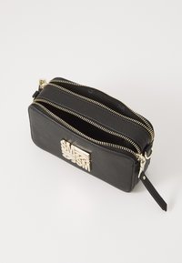Pochette nera in ecopelle con doppi scomparti, dettagli della cerniera in tonalità oro e un accento del logo metallico sulla parte frontale.
