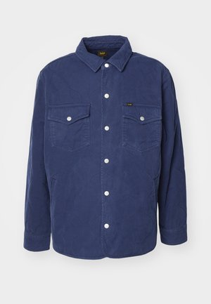 Giacca camicia trapuntata blu navy con due tasche sul petto, bottoni a scatto e colletto classico. Caratterizzata da un motivo testurizzato e vestibilità ampia.