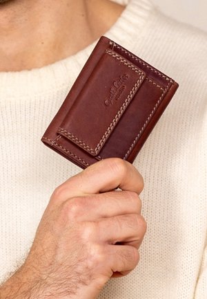 Brown leather wallet with a textured finish, featuring contrast stitching and a card slot. Compact design held in a hand.