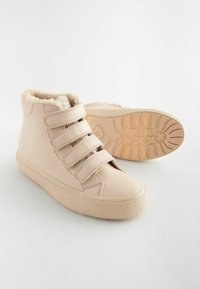 Beige High-Top-Schuhe mit drei Klettverschlüssen, Kunstfellfütterung und strukturiertem Gummisohle. Glattes synthetisches Obermaterial und abgerundete Zehenform.